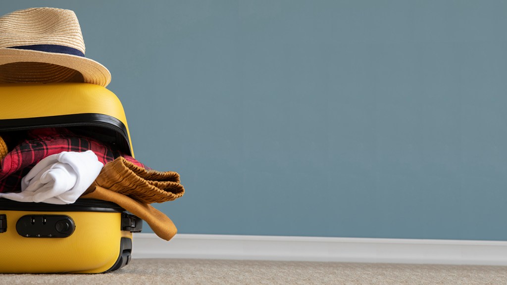 Travel items on the floor in a grey background.